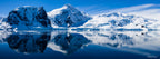 Panoramic photograph of snowy mountains reflected in the still waters of Neko Harbour, Antarctica, captured by landscape photographer Robert Vine.
