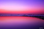 Fine art landscape photograph of Newcastle Canoe Pool at dawn — pink and violet sunrise reflecting over still water with anchored ships on the horizon, Australian coastal landscape art print by Robert Vine.