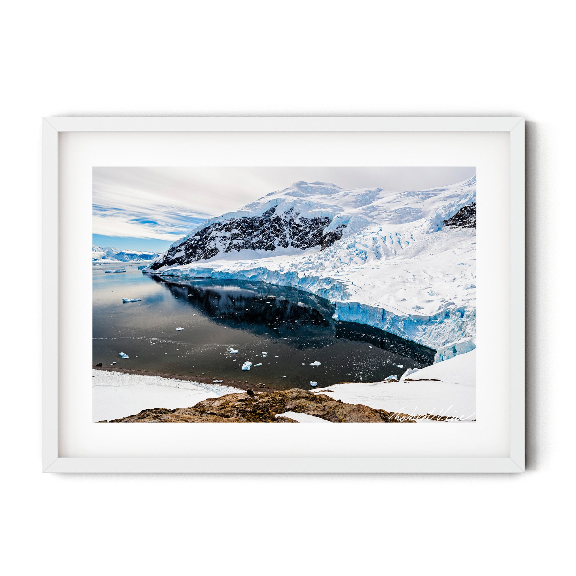 A sweeping Antarctic landscape featuring the towering ice cliffs of Neko Harbour reflected in calm, dark water under soft polar light.