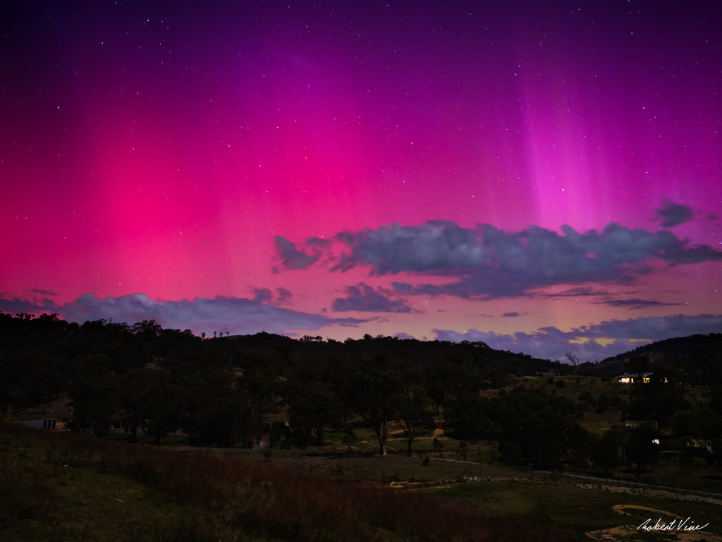 Aurora Australis glowing pink and purple over the hills of Royalla near Canberra beneath a star-filled night sky, photographed by Robert Vine.