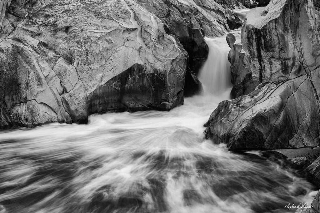Black and white photograph of flowing water cascading through sculpted granite rocks at the Googong Cascades, captured by Robert Vine.