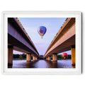 Framed print of the Air Force hot air balloon flying between Commonwealth Avenue Bridge spans with Parliament House in the background at dawn in Canberra.