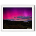 Framed landscape image of Aurora Australis glowing pink and purple over the hills of Royalla near Canberra beneath a star-filled night sky, photographed by Robert Vine.