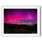 Framed landscape image of Aurora Australis glowing pink and purple over the hills of Royalla near Canberra beneath a star-filled night sky, photographed by Robert Vine.