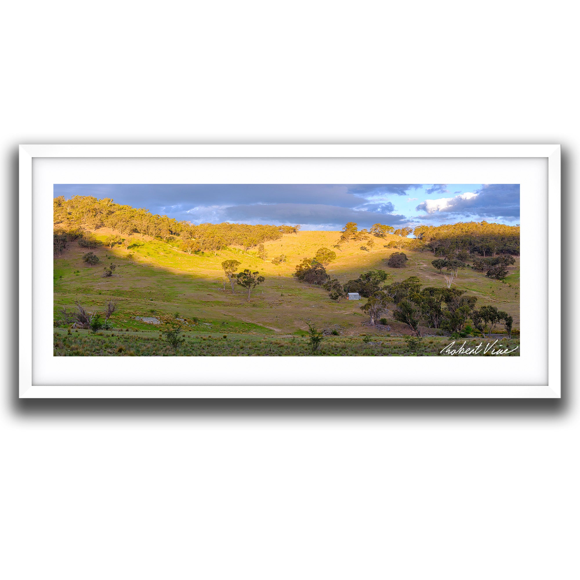 Framed print of Golden sunset light illuminating rolling hills and valleys near Burra beneath dramatic storm clouds, limited edition landscape art print by Robert Vine.