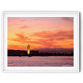 Framed print of The National Carillon illuminated at sunrise on Lake Burley Griffin, Canberra, beneath vibrant orange and pink clouds reflected across calm morning waters.