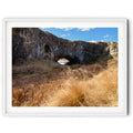 Framed print of an image of London Arch Bridge in Burra on a warm winter afternoon with golden grasses, rugged rock formations and blue sky, photographed by Robert Vine.