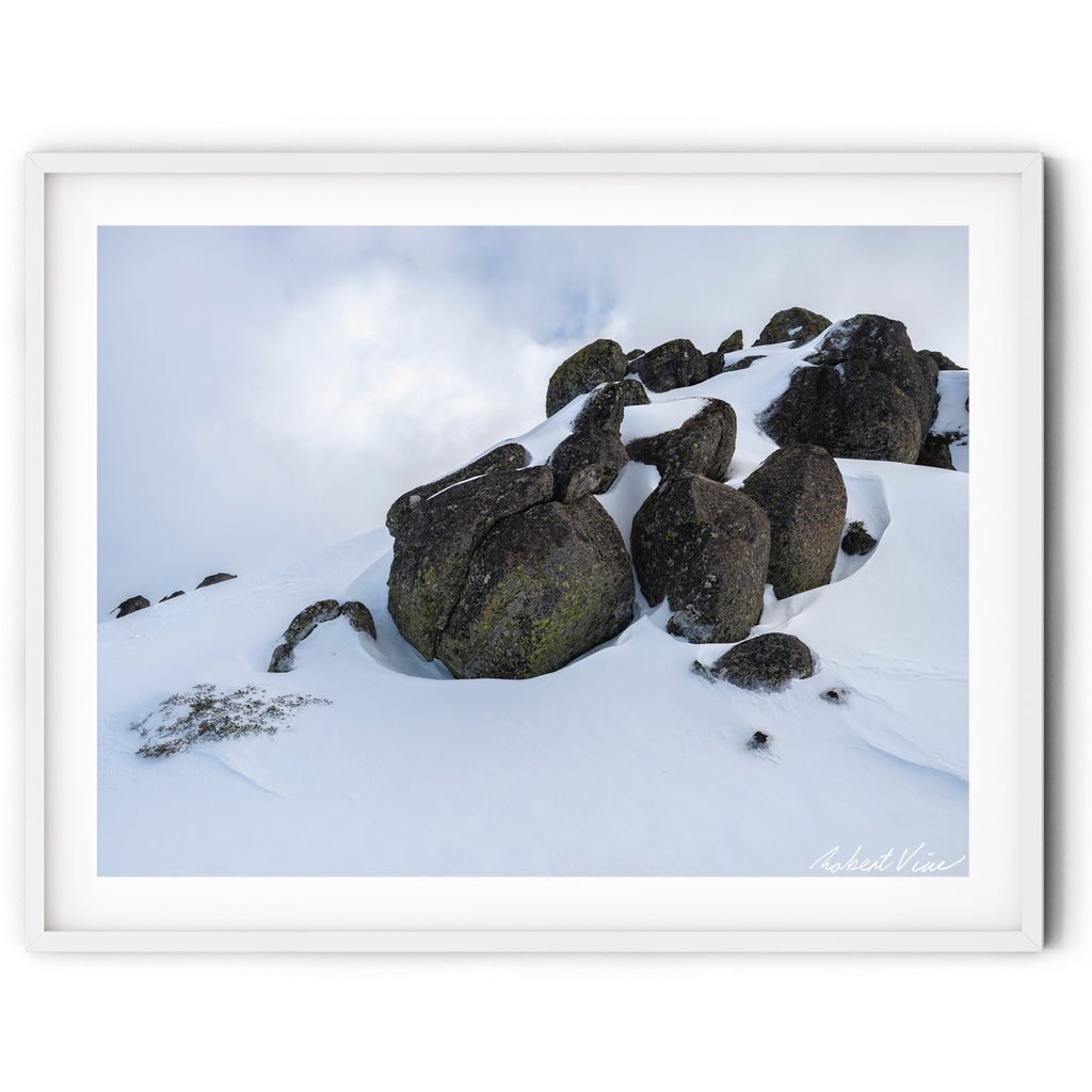 Framed art print of snow-covered granite boulders rising from pristine alpine snow beneath a cloudy sky near Thredbo in the Snowy Mountains, photographed by Robert Vine.
