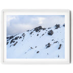 Framed wall art of a lone skier descending beneath snow-covered granite cliffs at Thredbo in the Snowy Mountains, photographed by Australian landscape artist Robert Vine.