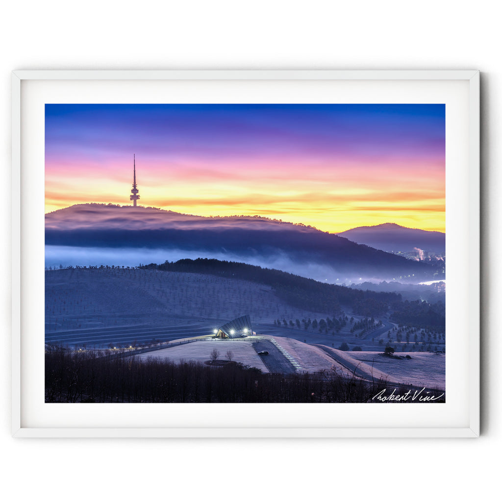 Framed print of Frost-covered hills at the National Arboretum Canberra with Black Mountain Tower silhouetted against a colourful sunrise and layers of mist drifting through the valleys.